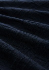 Dark blue fabric with a soft, textured surface, featuring subtle diagonal ribbing and waves created by folds.