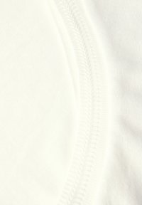 Puuvillakangas off-white värviga, millel on siledat tekstuuri ja kerge sära. Nähtav õmblusdetail servas kontrastse niidiga.