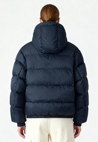 Doudoune bleu marine avec capuche, dotée d'un design matelassé, de poignets élastiques et d'un ourlet ajusté, réalisée en tissu lisse et isolant.