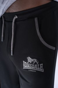 Mustat verkkohousut, joissa on harmaa nyöri, sivutaskut ja painettu leijonan logo sekä "Lonsdale London" -teksti lahkeessa. Pehmeä kangas.