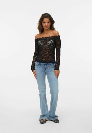 Zwarte kanten off-the-shoulder top met lange mouwen, gecombineerd met lichtblauwe flared jeans en zwarte met patronen versierde flats, met een complexe textuur en ontwerp.