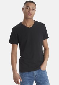 Svart bomull V-hals t-skjorte med korte ermer, glatt tekstur og tettsittende passform, kombinert med lyseblå denimjeans.