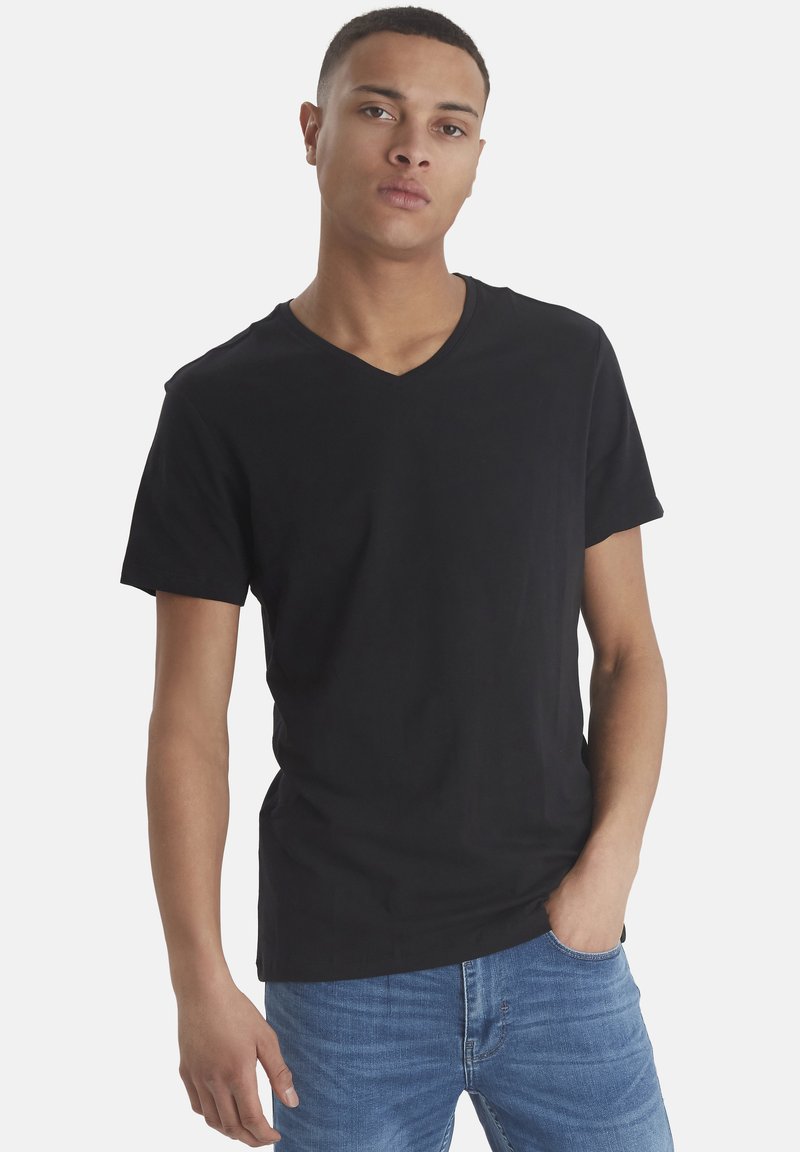 Svart bomull V-hals t-skjorte med korte ermer, glatt tekstur og tettsittende passform, kombinert med lyseblå denimjeans.