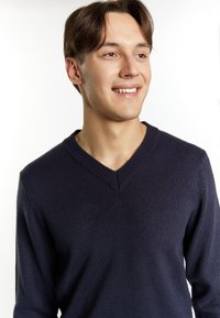 Marinblå stickad tröja med V-ringning, som har ribbade muddband och en texturerad yta. Mjuk material ger en avslappnad look för lager-på-lager styling.