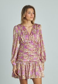 Vestido colorido con escote en V, mangas largas abullonadas y cintura fruncida. La tela presenta un vibrante patrón en rosa, amarillo y púrpura.