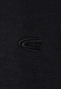 Tessuto a maglia nero con un piccolo e sottile logo ricamato a forma di tre linee curve che formano una "C" stilizzata in filo nero.