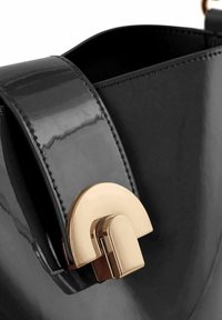 Bolso de mano de charol negro con un elegante cierre curvo en tono dorado y una textura lisa y brillante, con costuras detalladas a lo largo de los bordes.