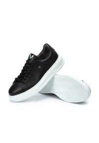 Sneakers in pelle nera con suola in gomma bianca, caratterizzati da punta rotonda, design con lacci e logo sulla linguetta. Motivo a rilievo sulla suola.