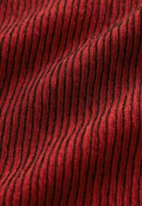 Tessuto con un motivo a coste, caratterizzato da strisce alternate rosse e nere. Texture morbida con dettagli del tessuto visibili in tutta la stoffa.