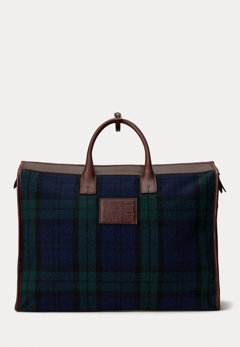 Tartan duffel bag featuring blue, green, and black checks. Brown leather accents and handles with a logo patch on one side. Zipper closure.