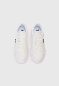 Un paio di sneaker bianche con lacci, decorate con motivi goffrati e etichette "Just Cavalli" sui lati, viste dall'alto su uno sfondo bianco.