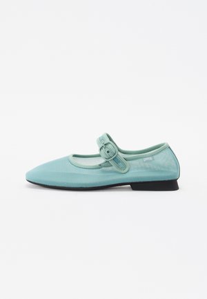 Scarpa stile Mary Jane in rete traslucida di colore verde menta con punta rotonda, fascia regolabile e tacco nero basso.
