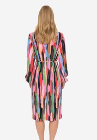 Meerlagige jurk met een patroon van verticale penseelstreken in roze, groen, blauw en zwart. Lange mouwen met een getailleerde taille.