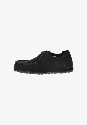 Chaussure décontractée en suède noir à lacets, avec une semelle texturée, des coutures de style mocassin et un logo Birkenstock sur le talon.