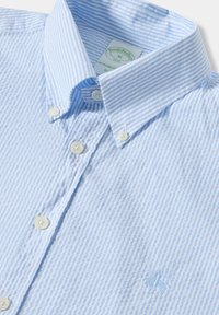 Camicia button-down a righe blu chiaro e bianche, con colletto, logo ricamato, con bottoni bianchi e tessuto testurizzato.