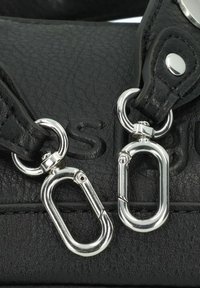 Black leather handbag featuring silver metal hardware, including two oval-shaped snap hooks and detailed stitching on the strap.