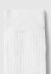 Calcetín blanco de canalé con una textura suave, que presenta un borde de punto y un diseño simple. Sin colores ni patrones adicionales.