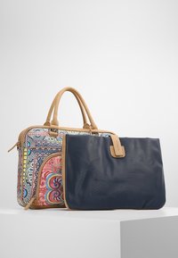 Set di borse doppie con una faccia in tessuto a fantasia colorata con accenti marroni e una borsa navy solida con manico in tan abbinato.