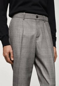 Pantalons à carreaux gris avec une finition soignée, dotés d'un devant plat, de poches latérales et d'une fermeture à bouton à la taille.