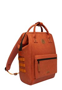 Sac à dos en simili cuir marron avec doubles poignées, une sangle ajustable, une poche zippée à l'avant et des sangles d'accent orange. Texture lisse avec des détails subtils.
