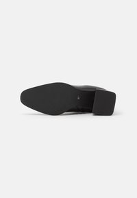 Black leather shoe with a wide, solid black heel. The sole is textured with grooves, and a size marking is visible on the inner side.