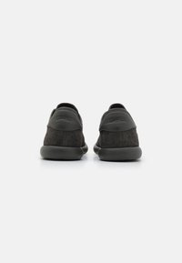 Chaussures en daim noir avec une semelle en caoutchouc lisse, un talon arrondi et un empeigne cousue. Présente un détail de logo à l'arrière et un design minimaliste.