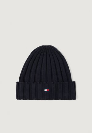 Jūrininkų mėlyna mezginė kepurė su raukšlėta tekstūra, kurioje ant sulenkto krašto yra mažas stačiakampis logotipas baltos, raudonos ir mėlynos spalvų.