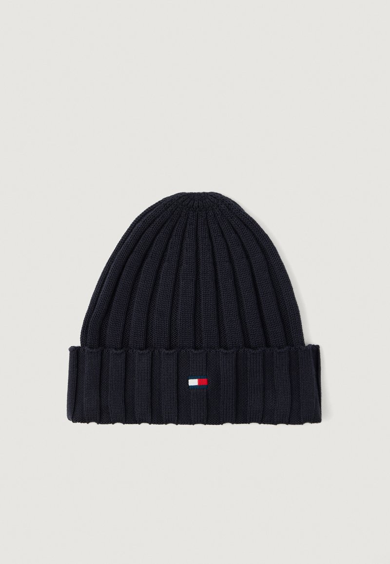 Marineblå strikket lue med ribbet tekstur, som har en liten, rektangulær logo i hvitt, rødt og blått på den brettede mansjetten.