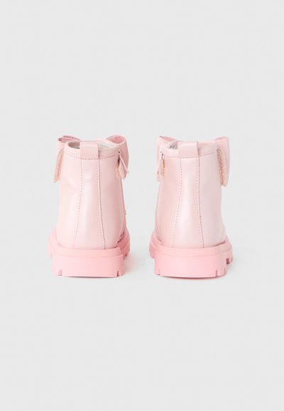 Bottines en cuir verni rose avec une finition lisse, dotées d'un petit talon et d'un détail de nœud décoratif à l'arrière.
