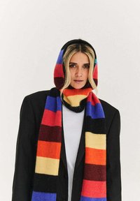 Wielokolorowy szal w paski, z wyrazistymi odcieniami czerwieni, niebieskiego i żółtego, wykonany z miękkiego materiału; noszony jako kaptur i owinięty wokół szyi.