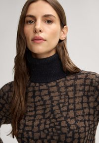 Rollkragenpullover in dunkelblau und braun, mit einem strukturierten Karomuster, aus einem weichen Strickmaterial, eng anliegendes Design.