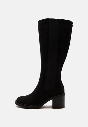 Botte noire mi-mollet avec talon bloc, panneau latéral élastique, texture lisse et languette à l'arrière.