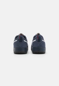 Navy blue sneakers with a suede upper, white accents, rear pull tab, and textured rubber sole. Two pairs shown from the back.