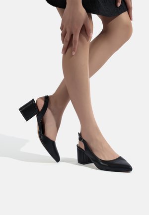 Tacchi slingback neri in pelle con punta appuntita e tacco a blocco spesso. Presentano una piccola fibbia e un design con parte posteriore aperta.