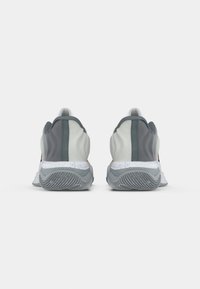 Αθλητικά παπούτσια σε γκρι και λευκό χρώμα, με υφή στη σόλα, λείο άνω υλικό και λουράκι στο πίσω μέρος.