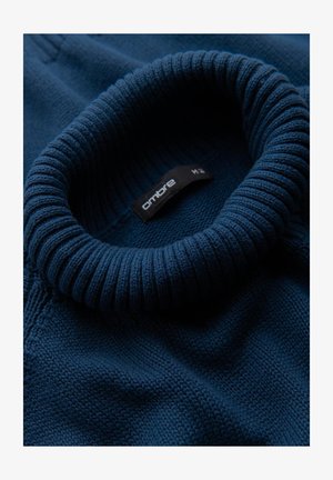 Navy gebreid sweater met een geribde hoge kraag. De stof heeft een gestructureerd patroon en een label met de tekst "ombre M." in close-up weergave.