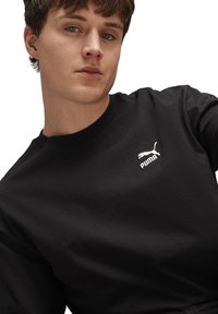 Felpa nera in cotone con girocollo e un piccolo logo Puma bianco sul lato sinistro del petto, con una vestibilità regolare e una texture morbida.