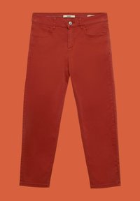 Pantalon slim rouge avec poches avant et fermeture à bouton sur fond orange.