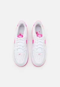 Valkoiset Nike Air -tossut, joissa on vaaleanpunaisia yksityiskohtia, pehmustettu sisus, rei'itetty varvasosa ja kumipohja, joka tarjoaa pitoa ja vakautta.