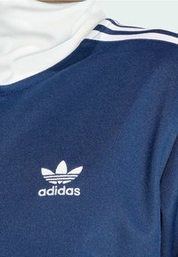 Marinblå sporttröja med vit mockakrage, tre vita ränder på axeln och en vit Adidas-logotyp på bröstet.