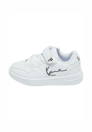White athletic shoe with a textured leather upper, round toe, velcro strap, and black signature detailing on the side and heel.