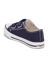 Sneakers in tela navy con suola in gomma bianca, caratterizzati da cuciture a contrasto e due cinturini in velcro per una vestibilità regolabile. Accentatura del tallone con logo.