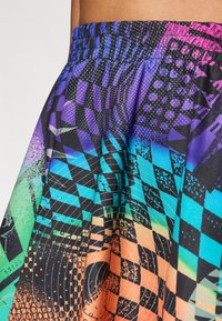 Pantalones cortos atléticos coloridos que presentan una mezcla de patrones geométricos en púrpura, azul, verde y naranja, con una cintura elástica para mayor comodidad.