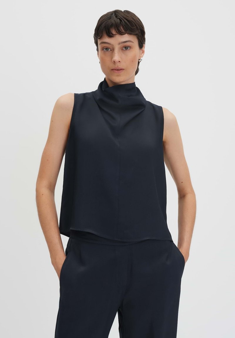 Top senza maniche in navy con scollo alto e vestibilità rilassata. Realizzato in tessuto morbido, presenta un design minimalista e senza chiusure visibili.