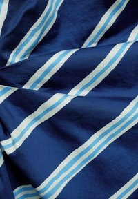 Tissu en coton bleu marine avec des rayures diagonales : bleu clair, bleu foncé et blanc. Texture lisse avec un contraste de couleurs vif.