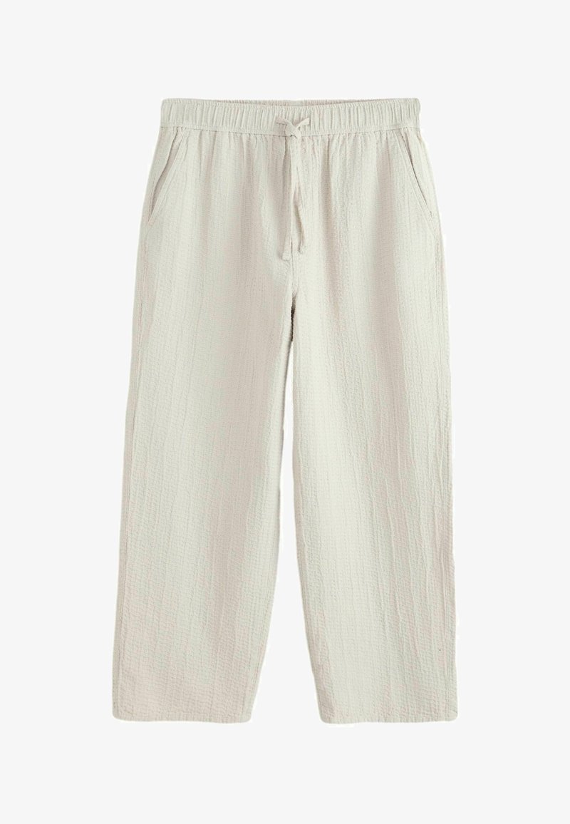 Pantalon en tissu beige clair texturé avec taille élastique, cordon de serrage et poches latérales, conçu pour une coupe décontractée.