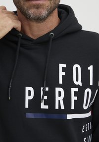 Felpa nera con cappuccio realizzata in cotone, caratterizzata da ampio testo bianco e una striscia orizzontale con dettagli in rosso e blu. Cords con punte in argento.