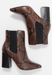 Bottines marron en cuir synthétique effet peau de serpent, avec bouts pointus, panneaux latéraux élastiques et talons blocs épais. Finition texturée avec accents brillants.
