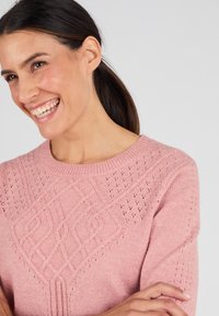 Lichtroze sweater met een gestructureerd diamanten patroon, ronde halslijn en korte mouwen, gemaakt van een zachte breimateriaal.