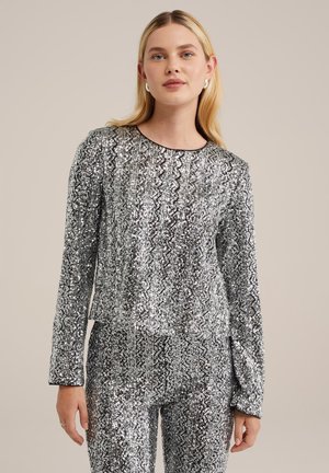 Top in paillettes argento con motivo a zigzag, maniche lunghe, scollatura rotonda e fit corto. Abbinato a pantaloni coordinati in paillettes.